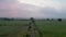 Dawn\'s veil: rising aerial of fields and dirt road under colourful sunrise