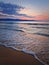 Dawn at the sea with foamy waves on the sand and colorful sky at the horizon. Sunny Beach coastline in Bulgaria. Summer and travel