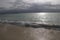 Dawn with stormy sky over the silver ocean. Lone fisherman boat in the water.