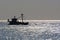 Day in the atlantic ocean. Silhouette of a fishing schooner and glare of bright light on the waves. A lot of sun