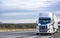 Day cab big rig white semi truck with roof spoiler transporting cargo in dry van semi trailer running in front of truck convoy on