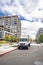 Day cab middle power rig semi truck with box trailer standing on the urban city street with multilevel apartment buildings