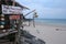 A day shot of a small wooden and bamboo shack on a white sand beach offering thai and oil massage services. The hut is on a small
