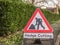 Day view hedge cutting warning sign in English town