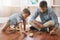 The day wont be complete without a little play. a young boy and his father playing with cars on the floor.