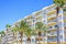 Daylight sunny view to city yellow hotel balconies on palm trees