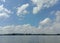 Daylight view of riverside with clouded blue sunny sky, rural riverside scene