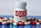 DDD - medical acronym on a white jar against the background of randomly scattered tablets