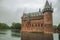 De Haar Castle facade with ornate brick towers and water moat on rainy day, near Utrecht.