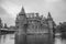 De Haar Castle facade with ornate brick towers and water moat on rainy day, near Utrecht.