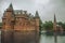 De Haar Castle facade with ornate brick towers and water moat on rainy day, near Utrecht.