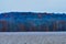 A Dead Crop Field in Winter With Multicolored Trees Behind It