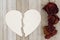 Dead red roses with torn heart-shape card on weathered wood back