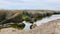 Dead tree, blue sky, moss rocks, marsh grasses, water with reflection.