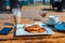 Deadpan image of pancake with honey, sour cream on wooden table with fork, spoon, smartphone and Cup of tea