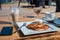 Deadpan image of pancake with honey, sour cream on wooden table with fork, spoon, smartphone and Cup of tea