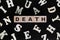 Death concept. Word death spelled in wooden blocks in dark black background.