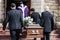 Death, funeral and holding coffin in church for grief, bereavement and with family together on steps. Grieving, sad and