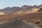 Death Valley - Panoramic view of endless empty road leading to colorful geology of multi hued Artist Palette rock formations