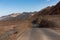 Death Valley - Panoramic view of endless empty road leading to colorful geology of multi hued Artist Palette rock formations