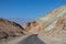 Death Valley - Panoramic view of endless empty road leading to colorful geology of multi hued Artist Palette rock formations