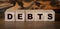 Debt wooden cubes with letters on wooden background. Financial concept