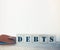 Debt wooden cubes with letters on wooden background. Financial concept