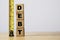 Debt wording stacking on wooden block cube with yellow tape measurement for debt analysis concept