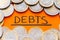 `Debts` text with coins around. Rising debt and inflation.