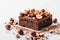 Decadent brownie slice adorned with hazelnuts, on pristine white canvas