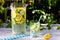 A decanter of cool water with slices of lemon and lime on a light wooden table.