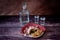 A decanter of vodka, two glasses and a plate with an assortment of meat snacks on a wooden table