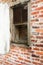 Decaying wood window in stucco and brick wall