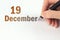 December 19th. Day 19 of month, Calendar date. The hand holds a black pen and writes the calendar date. Winter month, day of the