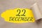 december 22. 22th day of the month, calendar date.Hole in paper with edges torn off. Yellow background is visible