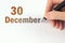 December 30th. Day 30 of month, Calendar date. The hand holds a black pen and writes the calendar date. Winter month, day of the