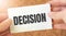 DECISION word inscription on white card paper sheet in hands of a businessman. recap concept. red and white paper