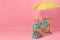 Deck chair, suitcase and beach accessories on pink background, space for text