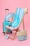 Deck chair, suitcase and beach accessories on pink background. Summer vacation