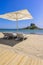 Deck chair and umbrella on beautiful Agios Stefanos Beach in front of paradise Island Kastri- historical ruins and paradise