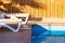 Deck chairs near swimming pool site rustic relaxation space on villa back yard sunny lighting shadow from palm on background