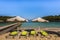 Deck chairs and sunshade beach umbrellas on the golden Ksamil beach with small islands in the turquoise sea, Albania