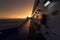 Deck of ferry sailing across the sea during last moments of a beautiful sunset with arriving land in the background. Concept of