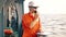 Deck Officer on deck of offshore vessel holds VHF walkie-talkie radio