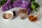 Decoction of lilac flowers Syringa vulgaris, oat bran, honey and essential oil close-up on a marble background.