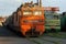 Decommissioned orange and green soviet locomotives stand on overgrown railway in abandoned stock