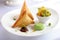 deconstructed samosa plate with crispy pastry triangles, spiced potatoes, peas, and chutney arranged beautifully on a white dish