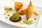 deconstructed samosa plate with crispy pastry triangles, spiced potatoes, peas, and chutney arranged beautifully on a white dish