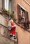 Decor in form of Santa Claus hangs on wall of house. Funny traditional Christmas decoration, toy Santa with bag of gifts climbing