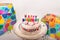 Decorated Birthday cake happy birthday candles on cake stand wrapped gifts on solid background